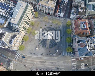 Aus der Vogelperspektive erhebt sich das weiße Nationaldenkmal vom Dam-Platz, umgeben von geometrischen Mustern von Pflastersteinen und Gebäuden, Amsterdam, Nord-Holland, Niederlande. Stockfoto