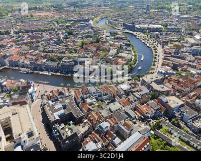 Aus der Vogelperspektive auf den sich windenden Fluss, der durch das Herz der Stadt fließt und den Himmel reflektiert, mit Gebäuden entlang der Ufer, Amsterdam, Nordholland, Niederlande. Stockfoto