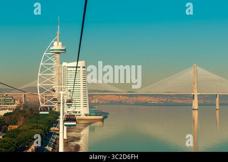 Aus der Vogelperspektive auf den Vasco da Gama-Turm und die Brücke über den Tejo. In Lissabon, Portugal, sind im Vordergrund Seilbahnen zu sehen. Stockfoto