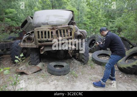 7. Juni 2019 - Pripyat, Ukraine - Ein Besucher fotografiert ein unglückliches Auto in der Tschernobyl-Sperrzone in der verlassenen Stadt Pripyat. Die HBO-Miniserie Tschernobyl, die am 2019. Mai in den USA und England Premiere hatte, zeigt die Folgen der Katastrophe, einschließlich der Säuberungsarbeiten und der anschließenden Untersuchung. Der Erfolg der HBO-Fernsehminiserie Tschernobyl, die den schlimmsten Atomunfall der worldâ in Tschernobyl untersucht hat, hat die Zahl der Touristen, die das Werk und die geisterhafte verlassene Stadt, die es benachbart, für sich gesehen haben wollen, in die Höhe getrieben und die Tourismusbranche der Region gestärkt. Stockfoto
