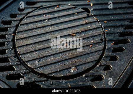 Ein schwarzes Grillgitter mit einem Loch in der Mitte. Das Gitter ist schmutzig und enthält einige Lebensmittelpartikel. Stockfoto