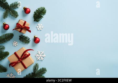 Weihnachtsgeschenke aus braunem Kraftpapier mit roten Samtbändern und Zweigen von immergrüner Tanne auf blauem Hintergrund. Platz für Ihren Text. Stockfoto