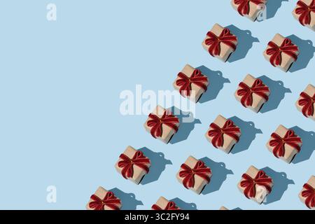 Horizontales Banner mit Muster von braunen Kraftgeschenkboxen mit roten Samtschleifen auf hellblauem Hintergrund. Platzieren für Ihren Text. Stockfoto