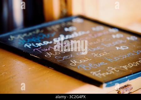 Alkoholische Cocktailkarte an der Bar. Holzbrett mit handgeschriebenen Kreidebeschriftungen. Sommerabend. Fazana, Kroatien - um 2025 Stockfoto