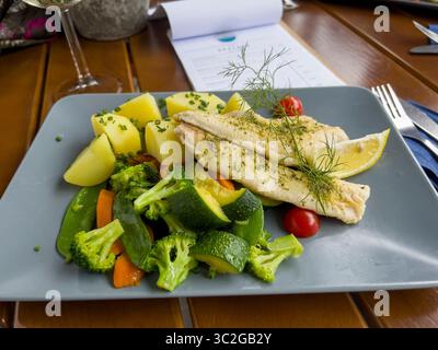 Forelle mit Kartoffeln, Kirschtomaten, Zucchini und Bohnen. Stockfoto