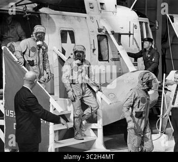 24. Juli 1969 - Florida, USA - in biologischen Isolationsbekleidung zogen sich die Apollo 11 Crew-Mitglieder (L-R) Edwin Aldrin, Neil Armstrong (Waving) und Michael Collins aus dem Rettungshubschrauber, um nach dem Spritzen an Bord des U.S.S. Hornet Flugzeugträgers zu gehen. Die Bergungsoperation fand im Pazifik statt, wo die Rettungskräfte der Marine die Kapsel mit der 3-Mann-Besatzung Apollo 11 geborgen haben. Die Besatzung wurde an Bord der U.S.S. Hornet in Sicherheit gebracht, wo sie in einer Mobile Quarantine Facility (MQF) untergebracht wurden. Diese tragbare Einrichtung diente als Zuhause, bis sie die NASA Ma erreichten Stockfoto