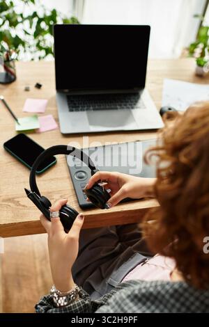 Eine junge Frau mit lockigen Haaren konzentriert sich auf ihre Aufgaben, während sie in ihrer gemütlichen Wohnung arbeitet. Stockfoto