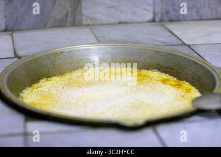 Nachdem du den Reis in den Kessel gelegt hast, während du den Plov gekocht hast, kommt das Wasser rein. Stockfoto