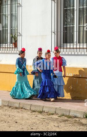 Frauen, die während der Pilgerfahrt El Rocio traditionell gekleidet in einer Straße spazieren gehen, El Rocio, Huelva, Andalusien, Spanien Stockfoto