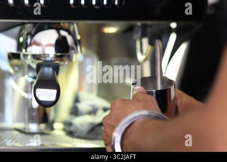 Cremona, Italien - 21. Juli 2025 professioneller Barista schäumt Milch im Metallkrug mit moderner Espressomaschine zur Kaffeezubereitung sorgfältig auf Stockfoto