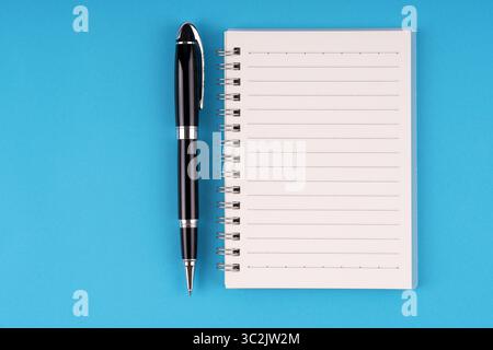 Notizblock und Stift auf blauem Hintergrund Stockfoto