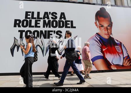 London, Großbritannien. Juli 2025. Vor dem Nike Store in der Oxford Street im Zentrum von London laufen die Leute an einem Werbespot vorbei, an dem England und Manchester United die Mittelfeldangreiferin Ella Toone zu sehen sind, bevor die Titelverteidigerin England und Spanien das Finale der UEFA-EM 2025 für Frauen ausführt. Quelle: SOPA Images Limited/Alamy Live News Stockfoto