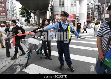 29. Juni 2019 - Osaka, Japan - Ein Polizist unterschreibt den Straßenverkehr, während eine Gruppe von Menschen, die gegen den G20-Gipfel 2019 in Osaka protestieren, vorbeifährt. Der Gipfel der Gruppe der 20 fand am 28. Und 29. Juni statt. Foto am Samstag, 29. Juni 2019. Foto: Ramiro Agustin Vargas Tabares (Foto: © Ramiro Agustin Vargas Tabares/ZUMA Wire) Stockfoto