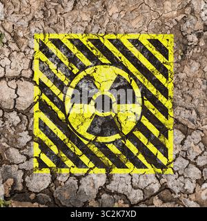 Gelbes radioaktives Zeichen auf gerissener trockener Erde, Draufsicht. Radiologische Verschmutzung Stockfoto