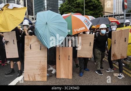 1. Juli 2019 - Hongkong, China - Anti-Regierungs-Demonstranten benutzen Regenschirme und hölzerne hausgemachte Schilde, um sich während der Auseinandersetzung vor der Polizei zu schützen. Tausende von regierungsfeindlichen Demonstranten standen während des 22. Jahrestages der Rückkehr Hongkongs zur chinesischen Herrschaft mit der Polizei und besetzen wichtige Straßen rund um den Regierungskomplex Hongkongs. (Credit Image: © Miguel Candela/SOPA Images via ZUMA Wire) Stockfoto