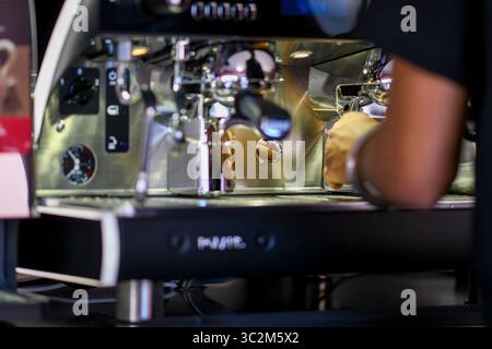 Cremona, Italien - 21. Juli 2025 der erfahrene Barista bereitet köstliche Kaffeegetränke mit der professionellen Espressomaschine zu Stockfoto