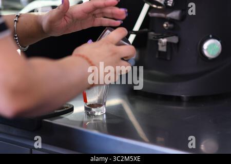 Cremona, Italien - 21. Juli 2025 Barista bereitet ein Kaffeegetränk vor und gießt heiße Milch in ein Shot Glass mit Espresso Stockfoto
