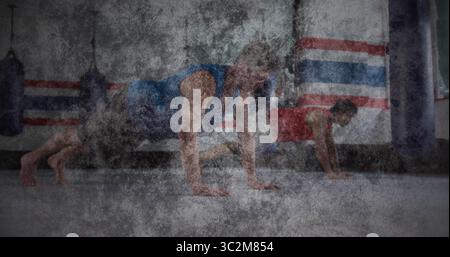 Männer, die Bergsteiger im Kampfsport-Fitnessstudio, in Tanktops mit Boxsäcken und Matten spielen. Fitness, Workout, Kraft, Entschlossenheit, Sportlichkeit Stockfoto