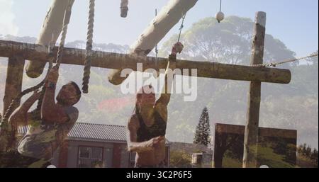 Kletterduo in Sportbekleidung, das Seilhindernisse auf dem Outdoor-Kurs mit Baumstämmen und Balken navigiert. Abenteuer, Teamwork, Resilienz, Outdoor, sportlich, Stockfoto