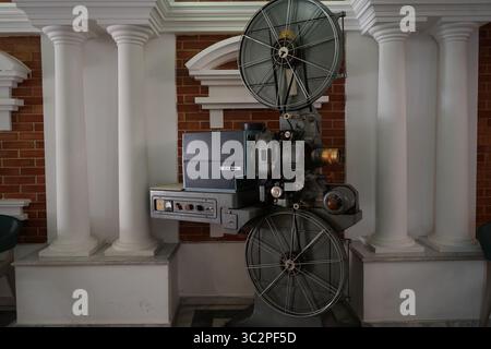 Ein klassischer 35-mm-Filmprojektor CX 21H in einem Kino im Vintage-Stil, umgeben von Säulen und roten Backsteinen, repräsentiert Retro-Filmtechnologie Stockfoto