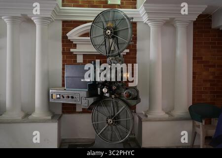 Ein klassischer 35-mm-Filmprojektor CX 21H in einem Kino im Vintage-Stil, umgeben von Säulen und roten Backsteinen, repräsentiert Retro-Filmtechnologie Stockfoto