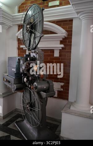 Ein klassischer 35-mm-Filmprojektor CX 21H in einem Kino im Vintage-Stil, umgeben von Säulen und roten Backsteinen, repräsentiert Retro-Filmtechnologie Stockfoto