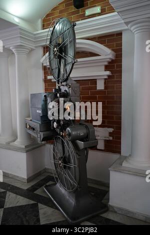 Ein klassischer 35-mm-Filmprojektor CX 21H in einem Kino im Vintage-Stil, umgeben von Säulen und roten Backsteinen, repräsentiert Retro-Filmtechnologie Stockfoto