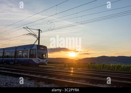 Traiskirchen: Zug der Lokalbahn Wien–Baden (Wiener Lokalbahn, Badner Bahn), Sonnenuntergang im Wienerwald, Wienerwald, Niederösterreich, Niederösterreich, Aus Stockfoto