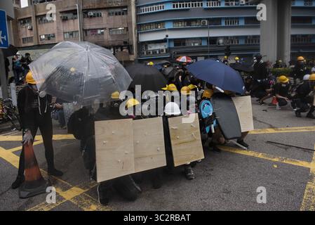 27. Juli 2019, Hongkong, China: Demonstranten nehmen Deckung während der Zusammenstöße mit der Polizei. Tausende Demonstranten setzen ihren wöchentlichen regierungsfeindlichen Protest fort und fordern die Regierung auf, das Auslieferungsgesetz vollständig zurückzuziehen und eine unabhängige kommission einzurichten, die die Probleme der Polizei mit unverhältnismäßiger Gewalt gegen Demonstranten untersucht und sich letzte Woche mit lokalen Bandenmitgliedern zusammenschließt, um Demonstranten anzugreifen. Der Protest fand im Bezirk Yuen Long statt, wo die Demonstranten letzte Woche von einem Mob von Bandenmitgliedern brutal angegriffen wurden, die in weiß gekleidet waren. (Kreditbild: © Miguel Candela/SO Stockfoto