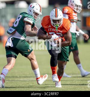 28. Juli 2019, Coral Gables, FL, USA: Miami Hurricanes Nachlauf Robert Burns (22) erhält eine Hand von Redshirt-Zweitquarterback Tate Martell (18) während der Herbstübung der University of Miami am Sonntag, 28. Juli 2019 im Greentree Field in Coral Gables, Fla. (Kreditbild: © TNS via ZUMA Wire) Stockfoto