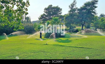Blick auf den grünen Rasen mit automatischem Bewässerungssystem auf dem Gelände eines Luxushotels in Griechenland an einem heißen Sommertag Stockfoto