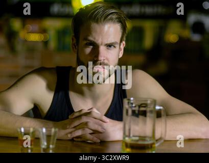Mann, der allein im Pub sitzt. Mann mit Alkohol. Trauriger Kerl in der Bar. Der Typ in der dunklen Bar. Alkoholproblem. Einsamer Mann trinkt Whiskey im Restaurant. Depressiver Mann Stockfoto