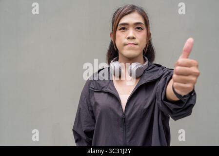 Porträt einer Transsexuellen-Asiatin vor einer normalen Außenwand mit Sportkleidung Stockfoto