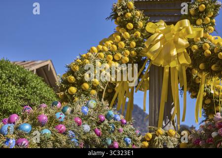 Osterbrunnen, Osterdekoration, ausgeblasene farbige Ostereier, Bäume, historische Gebäude, blauer Himmel, wolkenlos, Florianiplatz, Bad Reichenhall, Stockfoto