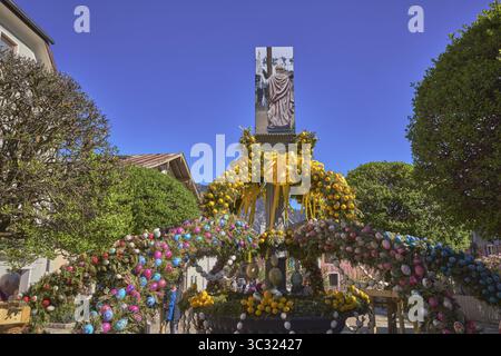Osterbrunnen, Osterdekoration, ausgeblasene farbige Ostereier, Bäume, historische Gebäude, blauer Himmel, wolkenlos, Florianiplatz, Bad Reichenhall, Stockfoto