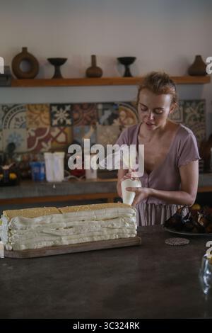 Nahaufnahme der Hände einer jungen Konditorin, die einen großen Geburtstagskuchen zubereitet Stockfoto