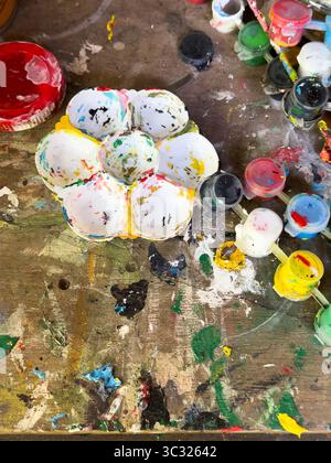 Eine lebendige Künstlerpalette mit farbenfrohen Farbspritzern auf einem Holztisch, die Kreativität und künstlerischen Ausdruck zum Ausdruck bringt. Stockfoto