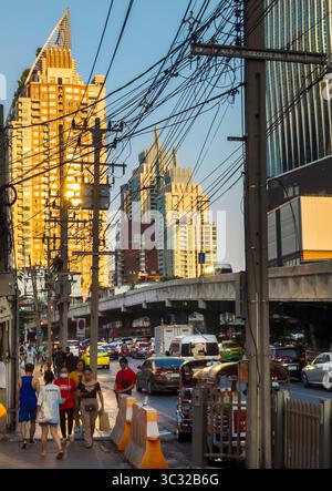 Bangkok, Thailand-07. April 2024-später Nachmittag, Sonnenlicht aus niedrigem Winkel reflektiert zufällig auf Hochhäuser und stark frequentierten Verkehr darunter während der Hauptverkehrszeit. Stockfoto
