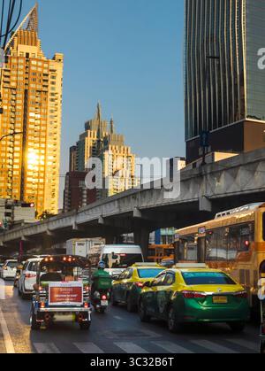 Bangkok, Thailand-07. April 2024-später Nachmittag, Sonnenlicht aus niedrigem Winkel reflektiert zufällig auf Hochhäuser und stark frequentierten Verkehr darunter während der Hauptverkehrszeit. Stockfoto