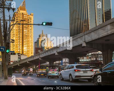 Bangkok, Thailand-07. April 2024-später Nachmittag, Sonnenlicht aus niedrigem Winkel reflektiert zufällig auf Hochhäuser und stark frequentierten Verkehr darunter während der Hauptverkehrszeit. Stockfoto