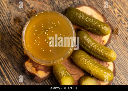 Eingelegte Gurken mariniert und eingelegte reife Gurken neben einem Glas, eingelegte Gurken mit Gewürzen und ganze knusprige Gurken auf ein Brett, Nahaufnahme Stockfoto