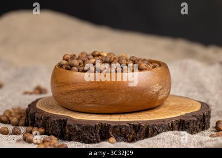 Geröstete Kichererbsen werden auf dem Tisch verstreut, gebratene, aber nicht gekochte Kichererbsen stehen auf dem Tisch mit einer Leinentischdecke, Brei wird in ein Holz gegossen Stockfoto
