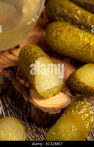 Eingelegte marinierte und eingelegte Gurken neben einem Glas, gegossene Gurken mit Gewürzen und ganze knusprige Gurken auf ein Brett Stockfoto