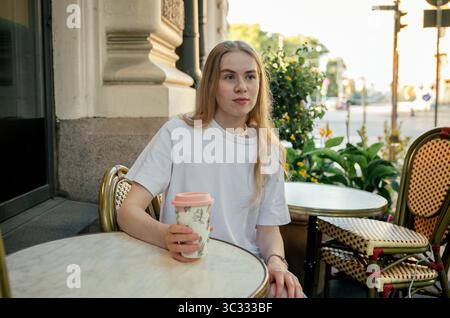 Frau, die allein am Kaffeetisch im Freien mit einer Tasse Kaffee in Helsinki sitzt Stockfoto