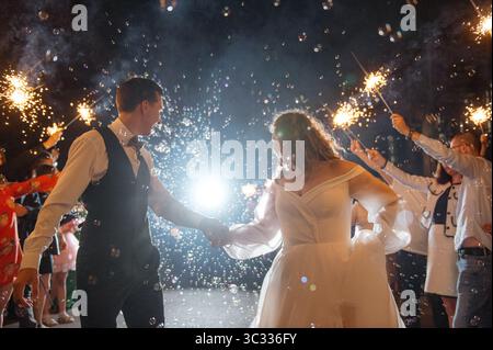 Ein Paar feiert die Hochzeit mit Glitzern und Seifenblasen in der Nacht Stockfoto