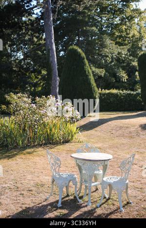 Vintage-Gartentisch und -Stühle in sonniger formeller Landschaft Stockfoto
