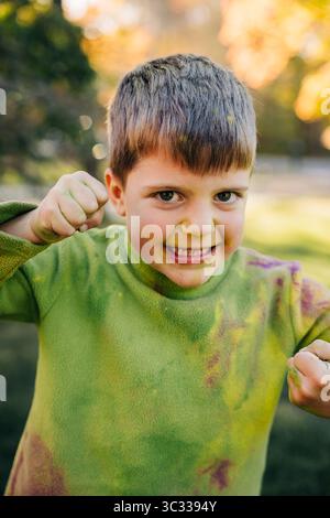 Kind spielt und macht lustige Gesichter, bedeckt mit holi-Farben Stockfoto
