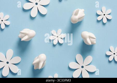 Minimalistisches Ostermuster mit weißen Häschen und Blumen auf blauem Hintergrund. Stockfoto