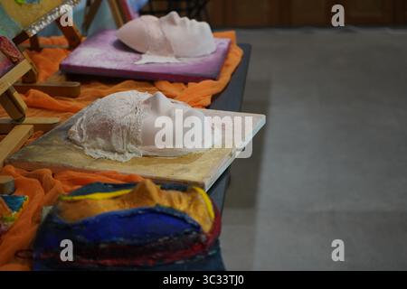 Gipsmasken auf Leinwänden in einer Kunstausstellung, die Textur, Handwerkskunst und künstlerischen Ausdruck mit lebendigem Stoff zeigen Stockfoto