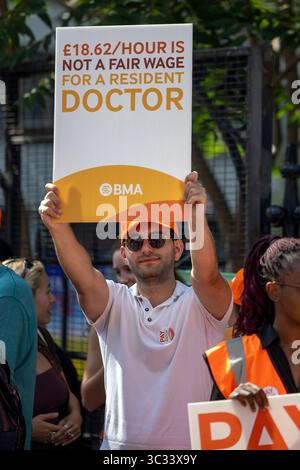 London, Großbritannien. 25. Juli 2025. Juniorärzte streiken vor dem St. Thomas’ Hospital, gegenüber den Houses of Parliament, am ersten Tag eines fünftägigen Rundgangs über Lohn- und Arbeitsbedingungen. Die Aktion, die von der British Medical Association (BMA) organisiert wurde, sah Ärzte, Mitarbeiter des NHS und gewerkschaftsvertreter, die Plakate skandierten und hielten, in denen die Labour-Regierung beschuldigt wurde, Versprechen über die Bezahlung des öffentlichen Sektors gebrochen zu haben. Die BMA fordert eine Gehaltserhöhung von 29 %, um die Gehälter wieder auf das Niveau von 2008 zu bringen, und nennt eine Lohnkürzung von 20 % in realen Bedingungen über 17 Jahre. Stockfoto